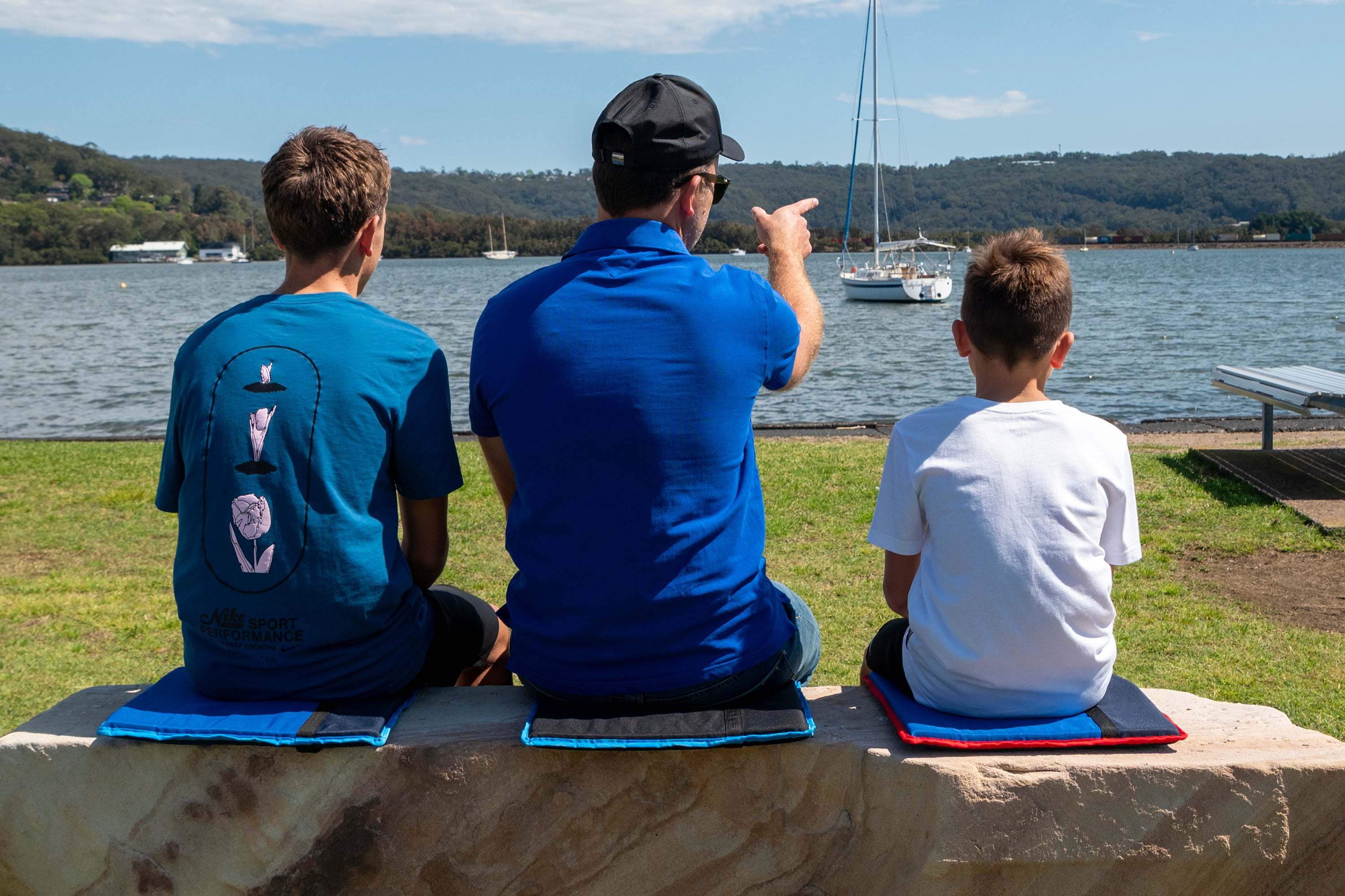 family sitting on park bench, stadium seat with strap, waterproof stadium cushion, lightweight sports seat, comfortable bleacher seat pad, best portable seat for game day, sports bench cushion, stadium seat Australia, bleacher back support seat, roll up stadium seat